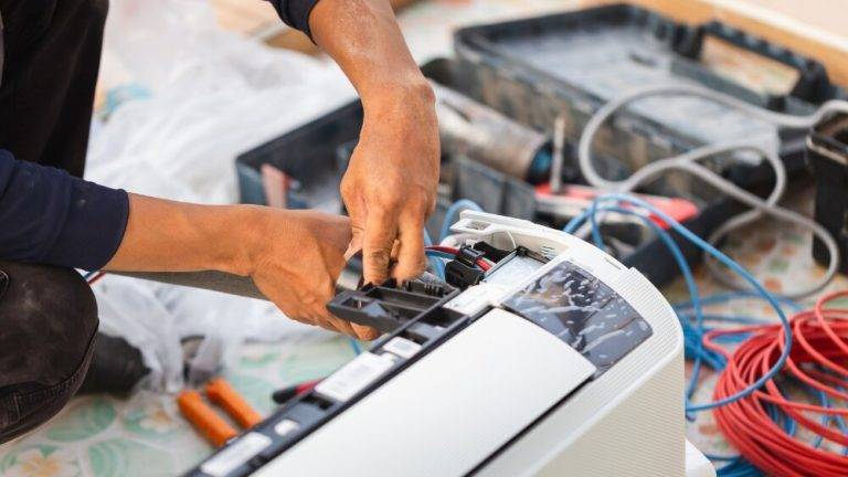Chatsworth AC repair expert fixing an air conditioning unit with various tools and wiring.