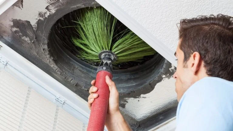 Affordable Heating and Air technician performing air duct cleaning with a rotating brush inside a ventilation duct in LA County.