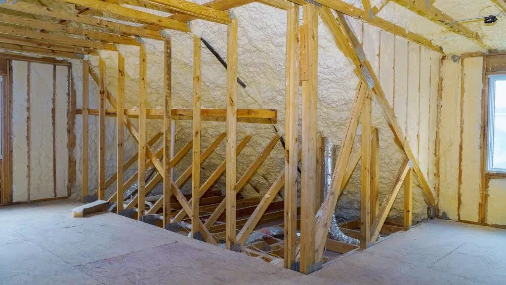 A room under construction with fiberglass insulation panels fitted between wooden beams in West Hollywood, CA.