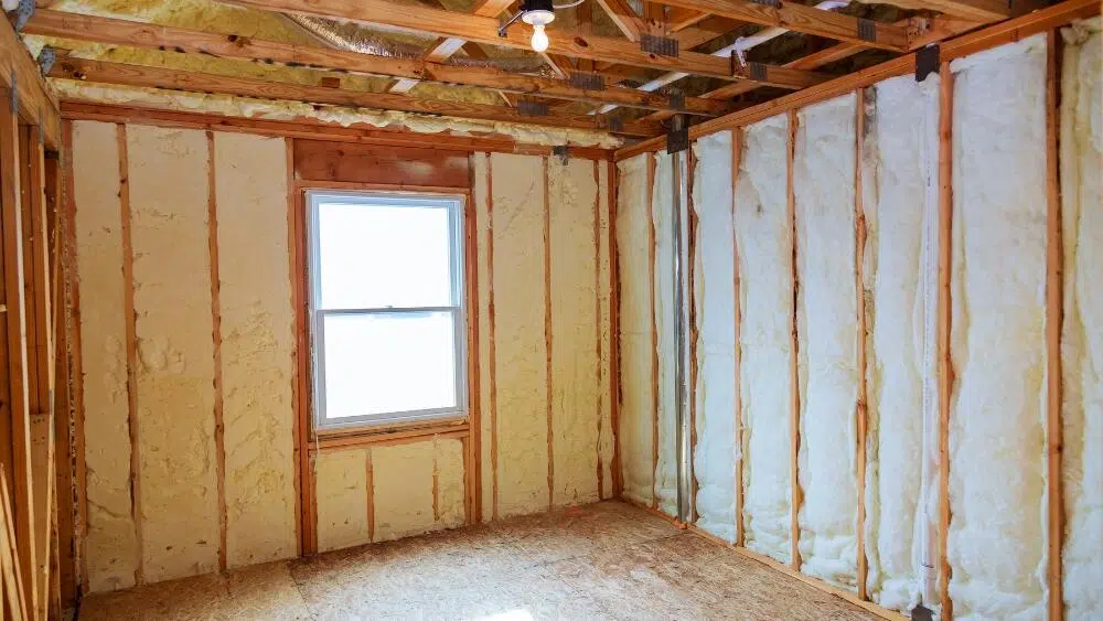 A room with exposed wooden framing and spray foam insulation applied between the studs, showcasing professional attic insulation services in West Hollywood, CA.