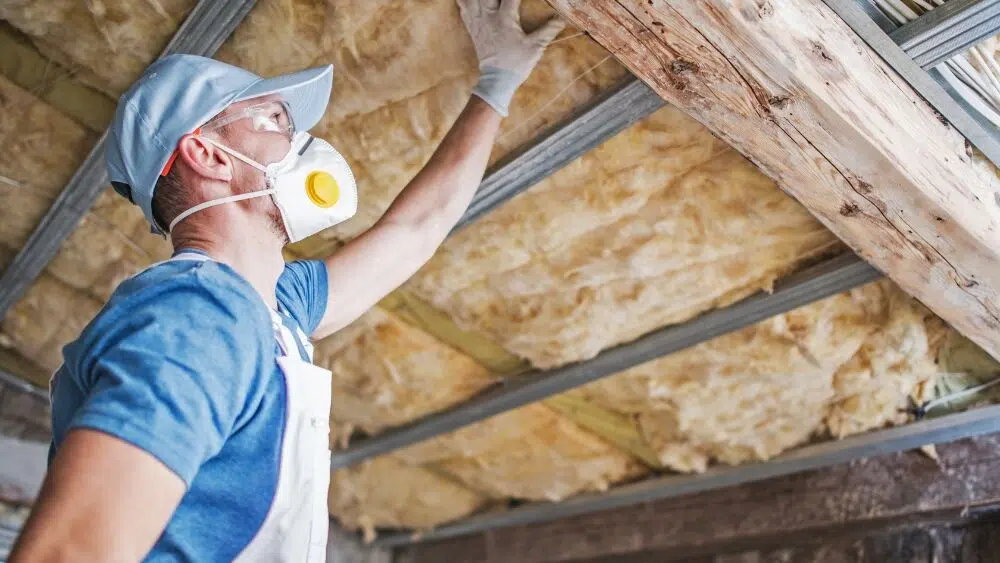 Affordable Heating and Air contractor wearing safety gear installing blown-in attic insulation in a home in West Hollywood, CA.