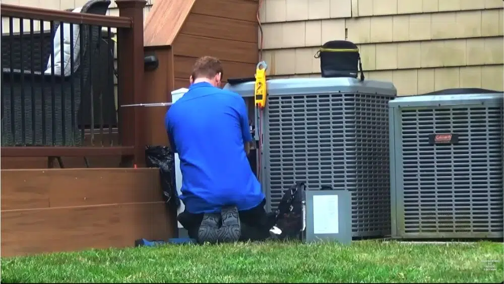Affordable Heating and Air’s technician providing emergency HVAC service in Beverly Hills, working on an outdoor AC unit beside a home.