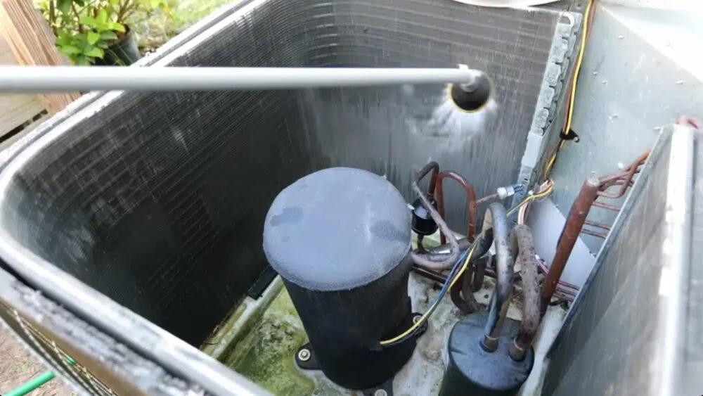 Person using a spray wand to clean the inside coils of an HVAC unit as part of a DIY AC tune up in Los Angeles County, CA.