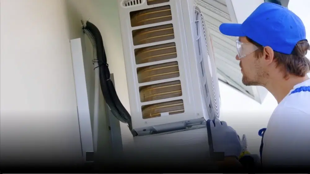 A technician inspecting an air conditioning unit for possible air quality issues.