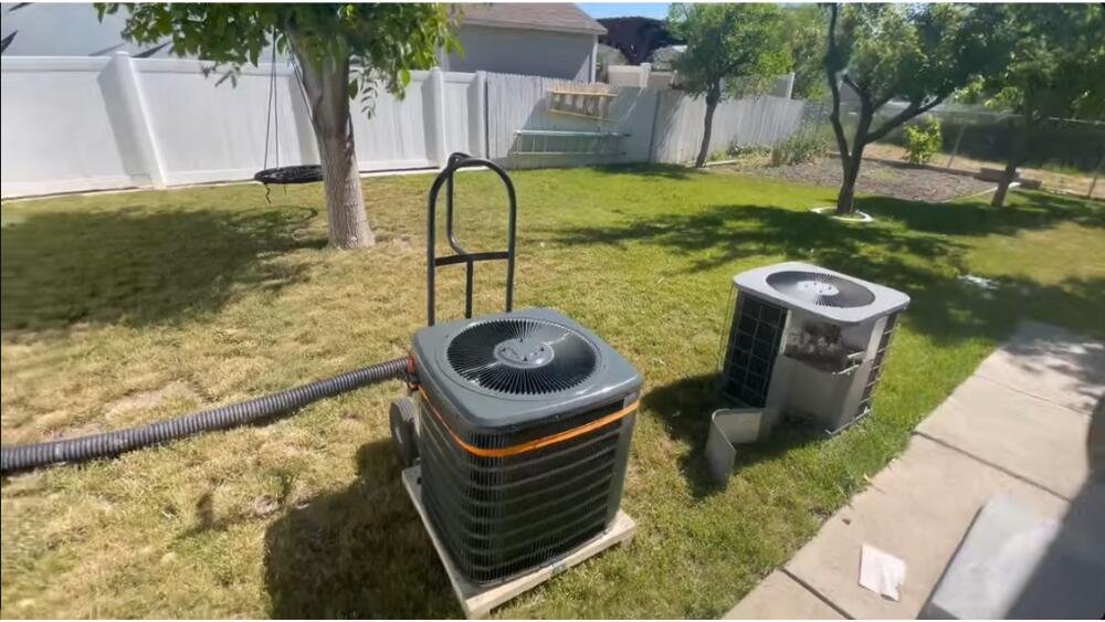 Two heat pump units on a lawn, one being newly installed while the old unit sits beside it during replacement in Santa Monica, CA.