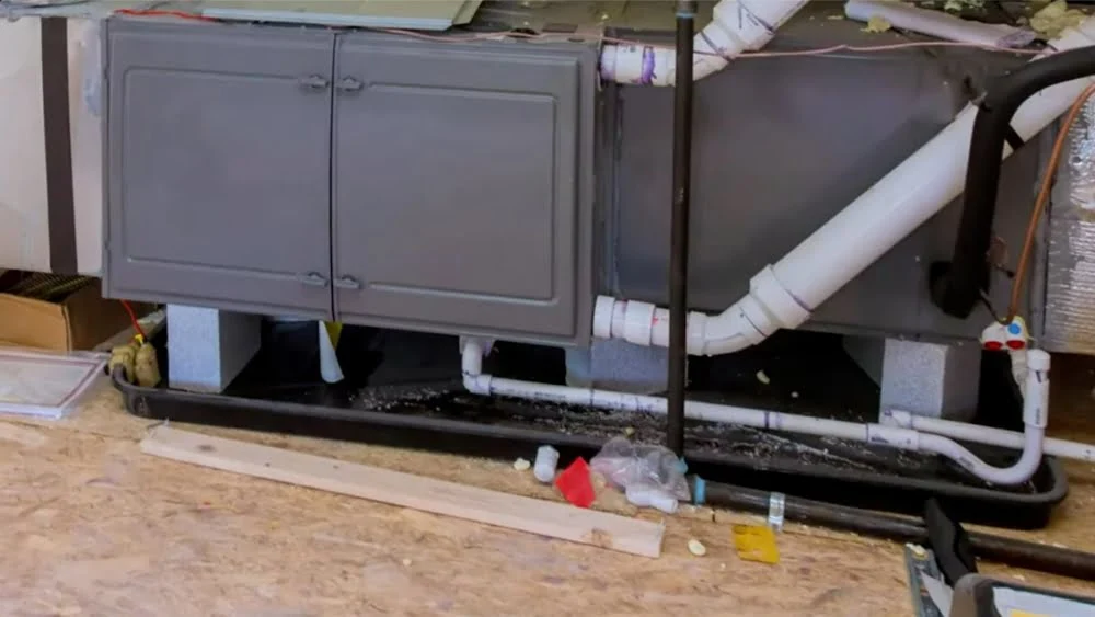 Horizontal attic air handler with PVC condensate lines and safety pan during HVAC repair in Agoura Hills, California.