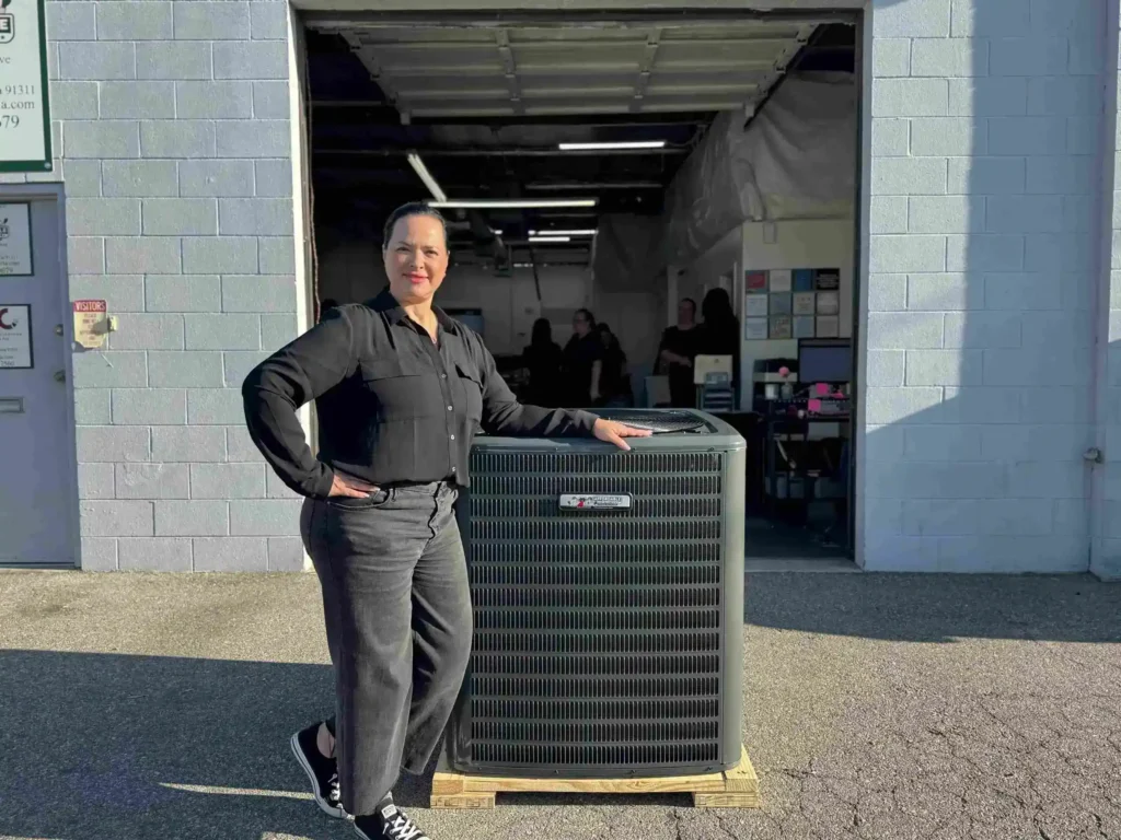 Donna Kreisler, owner of Affordable Heating and Air, showcasing high-efficiency air conditioner unit for HVAC services Ventura County.