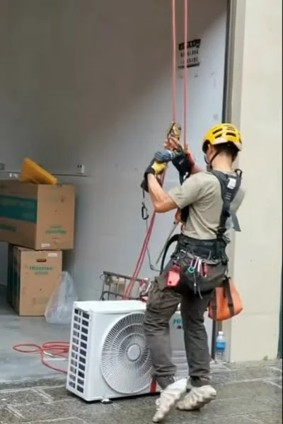 Certified technician using rope harness and safety gear to position outdoor AC unit during home AC replacement in Simi Valley