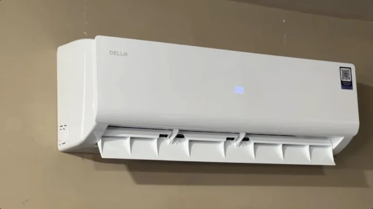 White DELLA ductless mini-split indoor air conditioning unit mounted high on a beige wall with adjustable airflow louvers open.