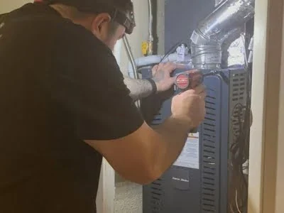 Affordable Heating and Air technician repairing a gas furnace and securing the vent connection in Calabasas CA.